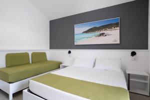 una camera con letto e sedia e una spiaggia di Istedda Boutique Hotel a Solanas