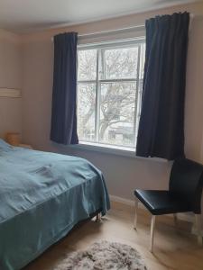een slaapkamer met een bed, een stoel en een raam bij Cosy apartment in the old west Reykjavik center in Reykjavík