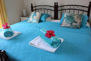 a blue bed with towels and flowers on it at STUDIO Apt Bright comfy with pool on South Coast in Bridgetown