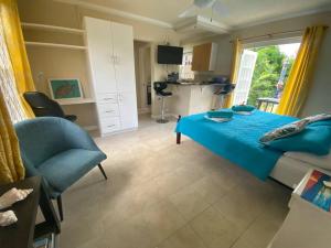 a bedroom with a blue bed and a kitchen at STUDIO Apt Bright comfy with pool on South Coast in Bridgetown