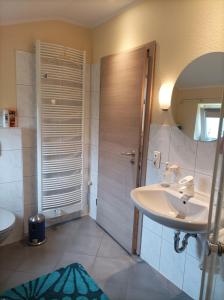 a bathroom with a sink and a shower with a mirror at Ferienwohnung Stapelmoor in Weener