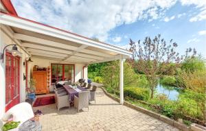 un patio con mesa y sillas junto a un río en Amazing Home In Genarp With Wifi And 3 Bedrooms, en Genarp