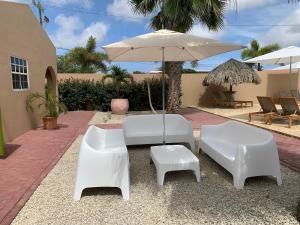 a patio with two white chairs and an umbrella at The Lizard Boutique Hotel in Kralendijk