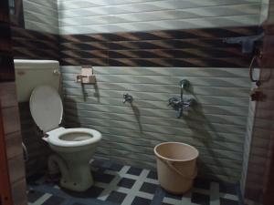 a bathroom with a toilet and a bucket at Hill Inn Rooms an HomeStay in Ooty