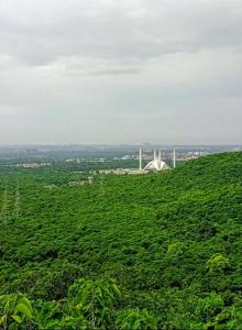 Una colina verde con un edificio blanco encima. en Heritage Inn, en Islamabad