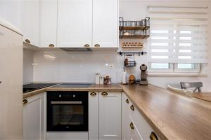 a kitchen with white cabinets and a wooden counter top at Apartment Ivy in Split