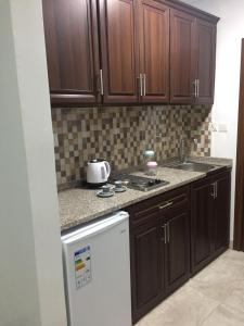 a kitchen with wooden cabinets and a white refrigerator at Tunaib Plaza in Aţ Ţunayb