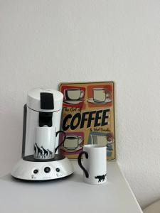 una cafetera y dos tazas en un estante en Möblierte Wohnung in Duisburg en Duisburg