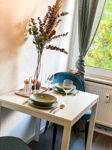 a table with plates and glasses and a vase with flowers at Apartment für 3 Gäste Messe- und Citynah in Hannover