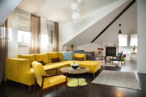 uma sala de estar com um sofá amarelo e uma mesa em Vila Ava em Zapresić