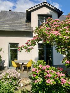 een tafel en stoelen voor een huis met roze bloemen bij Ferienhaus Ferienwohnung Potsdam DieGaLerie am Schlosspark Marquardt 