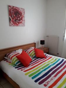 - un lit avec 2 oreillers rouges et une couverture colorée dans l'établissement Maison sur les hauteurs de Carcassonne, à Carcassonne