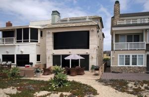 a large house with a patio with an umbrella at 5 Bedroom Beachfront Masterpiece in Huntington Beach