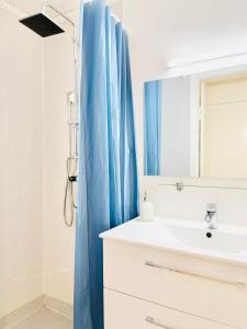 uma casa de banho com um lavatório e uma cortina de chuveiro azul em Scandinavian Apartment Hotel - Tobaksgården - 2 room apartment em Horsens