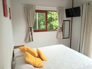 a bedroom with a bed with yellow pillows and a window at Casa da Ponte, Trindade in Trindade +13 photos