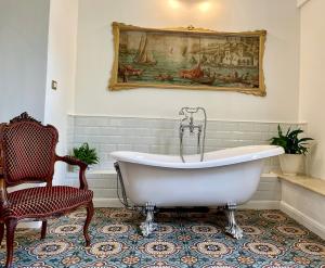 La salle de bains est pourvue d'une baignoire, d'une chaise et d'un tableau. dans l'établissement Villa Scinata Dimora Storica, à Nardò
