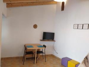 Habitación con mesa y TV en la pared. en Casa Algarvia G&S, en Luz de Tavira