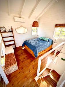 1 dormitorio con 1 cama en una habitación con suelo de madera en Casitas Punta del Diablo en Punta Del Diablo