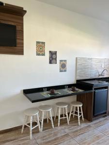 a kitchen with a counter with three stools in it at Pousada Floresta in Bombinhas
