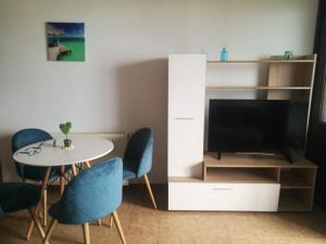 uma sala de estar com uma mesa e cadeiras e uma televisão em Mamaia Nord Apartament em Mamaia