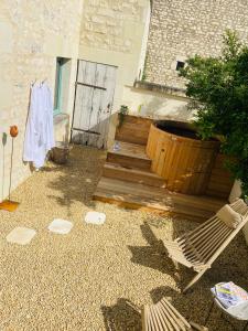 un patio con escaleras de madera y una silla en Gîte verveine bain nordique jacuzzi l écrin de verdure chinon, en Ligré