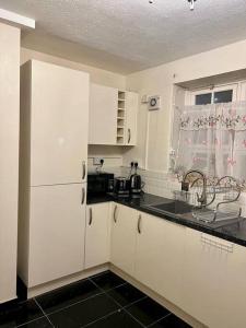 a kitchen with white cabinets and a black counter top at 2 Bedroom Flat in Vauxhall, London in London