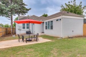 a patio with a table with a red umbrella at Modern Oklahoma City Home with Private Backyard! in Oklahoma City