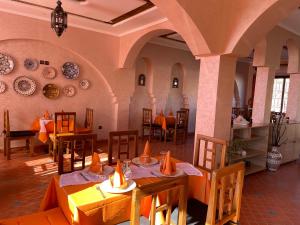 un ristorante con tavoli, sedie e piatti appesi al muro di Hotel Rayyan l 'Escale a Ouarzazate