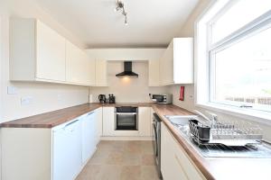 a kitchen with white cabinets and a window at Sleek 3 Bed in Bolton- Sky channels & BT sports in Bolton