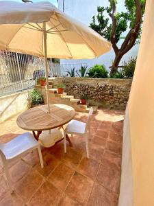 una mesa de madera y sillas con sombrilla en el patio en Bilocale Nucarella, en Scilla