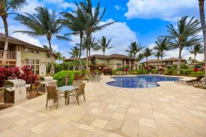 um pátio com uma mesa e cadeiras ao lado de uma piscina em Waikoloa Colony Villas #2105 em Waikoloa