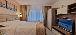 Cette chambre comprend un lit et une télévision à écran plat. dans l'établissement All In Jacuzzi Apartment, à Petroşani