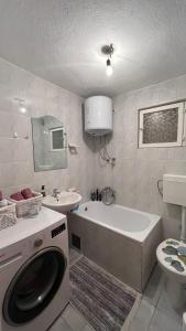 a bathroom with a tub and a sink and a washing machine at Sunlight Apartments in Mostar