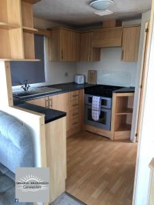 a kitchen with wooden cabinets and a stove top oven at Skegness - Ingoldmells Caravan Hire in Ingoldmells