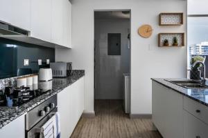 a kitchen with white cabinets and black counter tops at Comfy Apartment City Center - PH Quartier Atlapa in Panama City