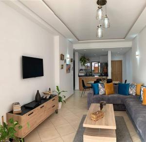 a living room with a couch and a tv at Beralmar Asilah Chez FATIMA in Asilah