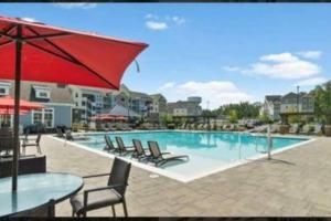 a swimming pool with chairs and a red umbrella at Cozy 2BR/2Bath Oasis 10 Minutes Away From Fort Lee in Brandermill