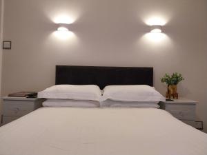 a bedroom with a large white bed with two lights at The Rosedene in Llandudno