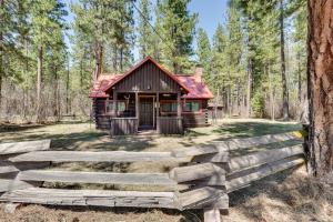 a log cabin in the woods with a wooden fence at Remote Escape Klamath Falls Cabin By Lake and Hikes in Klamath Falls