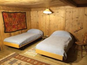 two beds in a room with wooden walls at Posta Veglia in Sils Baselgia