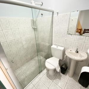 a bathroom with a shower and a toilet and a sink at Pousada Vila do Penedo in Penedo