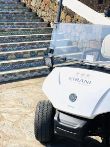 a white golf cart parked next to some stairs at Kirani Resort in Pantelleria