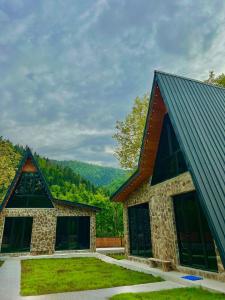 a stone house with a roof and a yard at Cottage Orcs in Borjomi