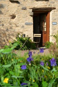 a table in front of a stone building with purple flowers at Maison d'une chambre a Perrigny sur Armancon in Perrigny-sur-Armançon