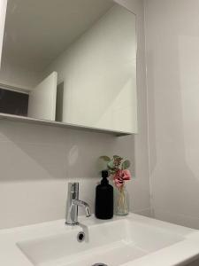 lavabo con espejo y jarrón de flores en Modern luxurious unit in the heart of Dickson en Canberra