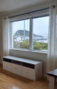 uma sala de estar com uma grande janela e um banco branco em Ålesund em Ålesund