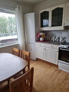 eine Küche mit einem Tisch und einem weißen Kühlschrank in der Unterkunft Ålesund in Ålesund