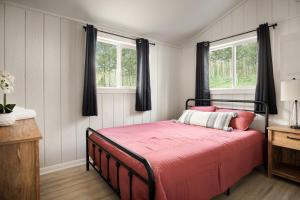 a bedroom with a bed with red sheets and two windows at Modern Cabin w Hot Tub, Wifi & Huge Deck! in Hedgesville