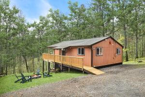 a small red cabin with a porch and a deck at Modern Cabin w Hot Tub, Wifi & Huge Deck! in Hedgesville