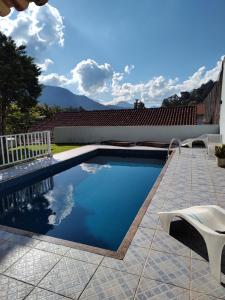 uma piscina com uma cadeira ao lado de uma casa em Quarto de solteiro/casais em Teresópolis